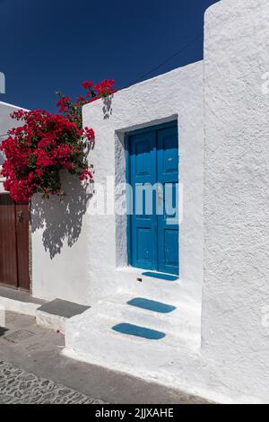 Tradition Griechische blaue Tür, weiß getünchtes Gebäude mit roten Blumen gegen einen blauen Himmel, Megalochori Dorf, Santorini, Kykladen Inseln, Griechenland, Europa Stockfoto