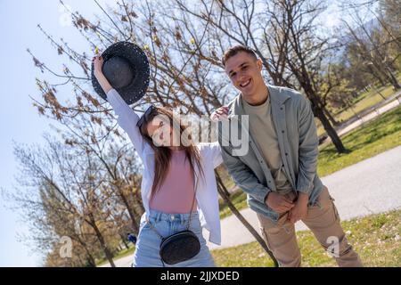 Fröhliche attraktive Mann und Frau mit viel Spaß im Freien, erzählen Witze, genießen warmen Tag. Foto in voller Länge Stockfoto