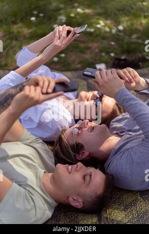 Drei unbeschwerte Teenager, die sich im Garten auf der Wiese Vergnügen Stockfoto