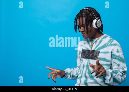 Ein dunkelhäutiger Mann schaut nach unten, während er Musik über Kopfhörer hört. Stockfoto