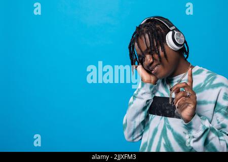 Ein dunkelhäutiger Mann schaut nach unten, während er Musik über Kopfhörer hört. Stockfoto