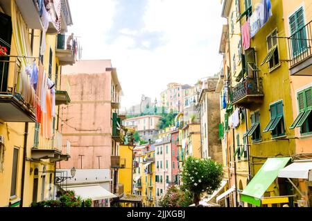 Riomaggiore Dorf, La Spezia Provinz, Ligurien, Norditalien. Blick auf die bunten Häuser auf steilen Hügeln, die Burg mit Uhr, Wäscherei auf balco Stockfoto