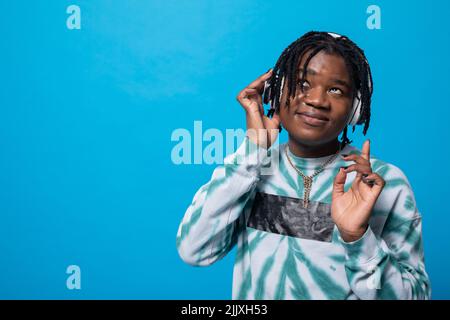 Während sie Musik hört, schaut ein dunkelhäutig gespielter Student nach oben. Stockfoto