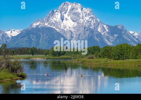 Die Bergkette des Grand Teton National Park wird an einem sonnigen Sommertag während eines Morgens mit den Spiegelungen der Gipfel im Snake River fotografiert. Stockfoto