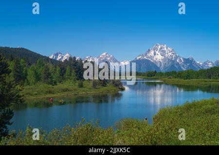 Die Bergkette des Grand Teton National Park wird an einem sonnigen Sommertag während eines Morgens mit den Spiegelungen der Gipfel im Snake River fotografiert. Stockfoto