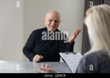 Nahaufnahme von lächelnden jungen kaukasischen Therapeutin oder Hausarzt haben Rücksprache mit alten männlichen Patienten in der Klinik oder im Krankenhaus. Glückliche Frau Arzt reden Stockfoto