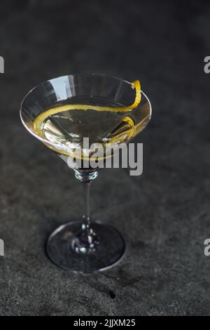 Martini mit einer langen Zitronenverdrehung auf Betonboden Stockfoto