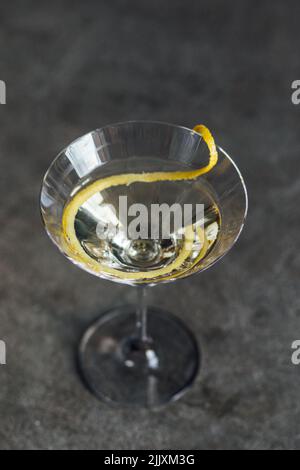 Martini mit einer langen Zitronenverdrehung auf Betonboden Stockfoto