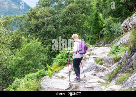 Ben Nevis, Schottland, Wanderfrau aus den fünfziger Jahren, mit Wanderstöcken, Wanderungen vom Berg Ben Nevis, entlang eines Steinpfades, Schottland, Großbritannien, Sommer 2022, Model releas Stockfoto