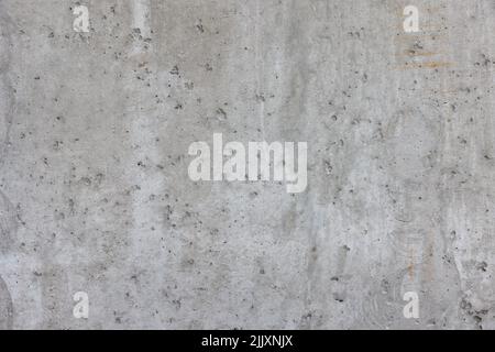 Grau geprägte Textur einer grauen Betonwand mit Schlaglöchern und Rissen, abstrakter Hintergrund. Stockfoto