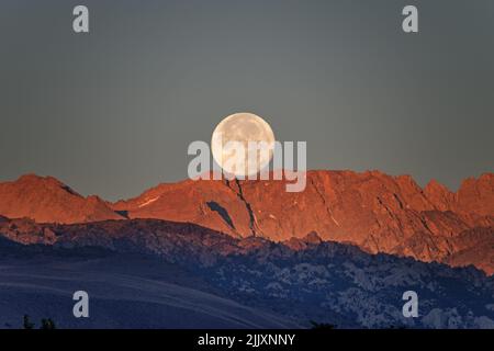 Der Vollmond untergeht bei Sonnenaufgang über dem Mount Lamarck in den Sierra Nevada Mountains, von Bishop California aus gesehen Stockfoto