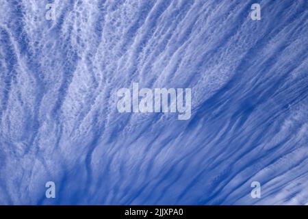 Wispy weiße Streifen Cirrus Wolken mit einem blauen Himmel hinter ihnen Stockfoto