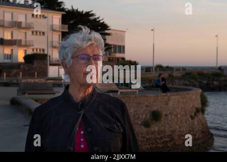 Porträt einer älteren Frau am Meer in der Bretagne bei Sonnenuntergang Stockfoto