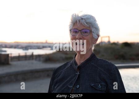 Porträt einer älteren Frau am Meer in der Bretagne bei Sonnenuntergang Stockfoto