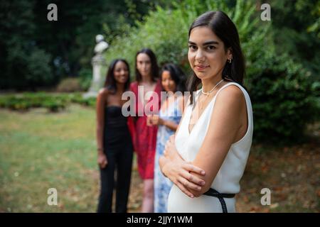 Nahaufnahme eines isolierten kaukasischen Mädchens mit ihren Freunden verschiedener Ethnien im Hintergrund, Konzept von Frauen und Vielfalt Stockfoto