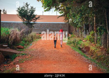 Die harte Arbeit und das Leben von Kindern in Afrika. Zwei kleine Kinder, die in Kenia auf einer Straße unterwegs sind. Eine herausfordernde Kindheit für junge Menschen in Afrika Stockfoto