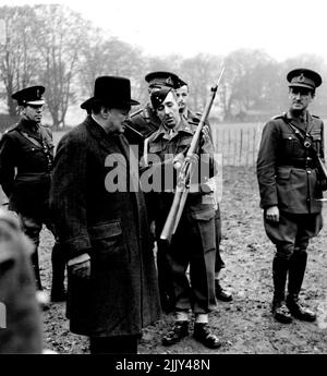 Churchill beobachtet Infanterie-Training - als Churchill eine Einheit sah, die mit einem neuen Gewehr und einem kurzen Bajonett ausgestattet war, untersuchte er sie genau. Lieut. General Ismay befindet sich auf der äußersten linken Seite und General Sir Bernard Paget auf der rechten Seite. Der Premierminister, begleitet von General Sir Bernard Paget (C-in-C-Truppen der Innenminister) und Lieut. General Sir Hastings Ismay (Militärberater des Kriegskabinetts) besuchte Truppen im Südosten und beobachtete verschiedene Abteilungen der Infanterieausbildung. Die meisten Truppen stammten aus Wales. 23. November 1942. (Foto von Fox Photos). Stockfoto