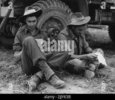 Mailformular Startseite -- mit einem LKW-Rad für eine Rückenlehne, zwei Mitglieder des Royal Australian Regiment jetzt im Dienst in Korea, Pvt. Gordon Nelson (links) aus Toowoomba, Queensland und Pvt. Gordon Mosey aus South Perth, nehmen Sie sich Zeit, um Briefe von zu Hause zu lesen. 8. Oktober 1950. (Foto von Associated Press Photo). Stockfoto