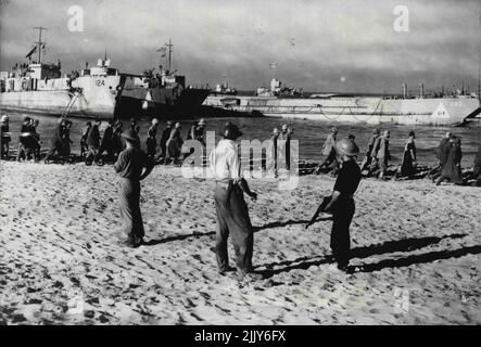 Die sizilianischen Landungen: Morgendämmerung 10. Juli 1943 - Dies ist eine von einer Serie von beeindruckenden Bildern, die kurz nach der Morgendämmerung am 10.. Juli von einem offiziellen Naval-Fotografen aufgenommen wurden, der die Sturmtruppe nach Sizilien begleitete. Sie zeigen etwas von der großen Rolle der Marine bei den erfolgreichen Landeoperationen - und danach. Kriegsgefangene marschieren am Strand entlang zu wartenden Schiffen, die von Naval Coomandes überwacht werden, von denen einer mit einer Tommy-Waffe bewaffnet ist. 11. Oktober 1943. (Foto von British Official Photograph). Stockfoto