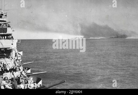 Die US-Marinestreitkräfte unterstützen alliierte Landungen in Sizilien -- Rauch steigt aus brennenden Achsenanlagen am Ufer in Livata, Sizilien, nach einem Bombardement durch den US-Kreuzer (links), von dem dieses Bild aufgenommen wurde, und andere alliierte Kriegsschiffe, als die ersten Invasionslandungen im Gange waren. Mehr als 1.500 Schiffe der US-Marine, von Kreuzern bis hin zu kleinen Landungsschiffen, die von 40.000 Offizieren und Männern besetzt waren, gehörten zu den 3.000 alliierten Schiffen, die an den gigantischen amphibischen Operationen teilnahmen. 29. August 1943. Stockfoto