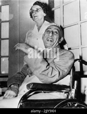 Happy Interlude - Premier Mohammed Mossadegh aus dem Iran lacht gerne, als er heute hier im New York Hospital während einer Fotokonferenz mit Nachrichtenleuten spricht. Krankenschwester Ruth Meacham steht hinter seinem Rollstuhl. Der iranische Staatschef ist in New York, um seine Seite im iranisch-britischen Ölraffinerie-Streit vor dem Sicherheitsrat der Vereinten Nationen zu vertreten. Er ist seit einiger Zeit krank und wohnt im Krankenhaus und nicht in einem Hotel. 12. Oktober 1951. (Foto von AP Wirephoto). Stockfoto