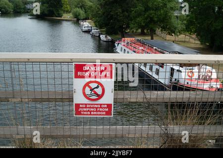 Windsor, Großbritannien. 28.. Juli 2022. Ein bestehendes Gefahrenschild auf der Brücke am Royal Windsor Way über der Themse. Nachdem in der vergangenen Woche der Leichnam eines Mannes von der Themse in der Nähe von Baths Island in Windsor geborgen wurde, wurden neben der Themse neue Gefahrenschilder angebracht, die die Menschen über die Gefahren des Schwimmens in der Themse informieren. Quelle: Maureen McLean/Alamy Live News Stockfoto