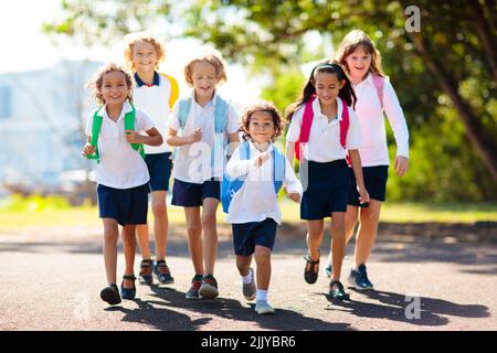 Die Kinder gehen zurück zur Schule. Interrassische Gruppe von Kindern unterschiedlichen Alters laufen und jubeln am ersten Tag des neuen akademischen Jahres. Beginn der Schulferien. Stockfoto