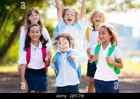 Die Kinder gehen zurück zur Schule. Interrassische Gruppe von Kindern unterschiedlichen Alters laufen und jubeln am ersten Tag des neuen akademischen Jahres. Beginn der Schulferien. Stockfoto