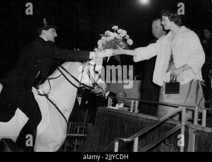 Cavalier's Bouquet - mit höflicher Geste lehnt sich der bekannte Reiter Albert Schumann aus seinem Sattel, um Prinzessin Alexandra von Kent heute Abend (Mittwoch) im Tom Arnold Christmas Circus in der Harringay Arena, North London, einen Strauß zu präsentieren. Albert Schumann, ein Star der Show, aus Kopenhagen, ist Mitglied einer bekannten dänischen Zirkusfamilie. 22. Dezember 1954. (Foto von Reuterphoto). Stockfoto