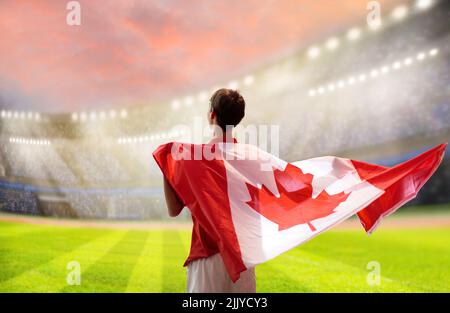 Fußballfan von Kanada im Stadion. Kanadische Fans auf dem Fußballplatz beobachten Mannschaftsspielen. Eine Gruppe von Unterstützern mit Flagge und Nationaltrikot Stockfoto