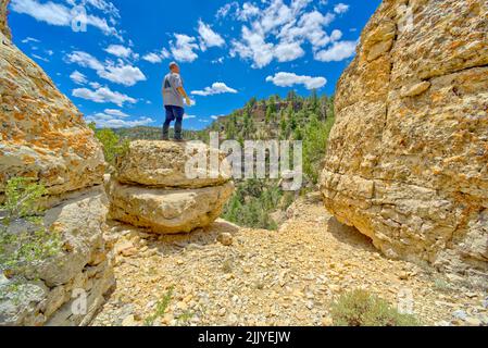 Ein Wanderer, der auf einem Felsbrocken am Rand einer Klippe am Grand Canyon Arizona steht. Stockfoto