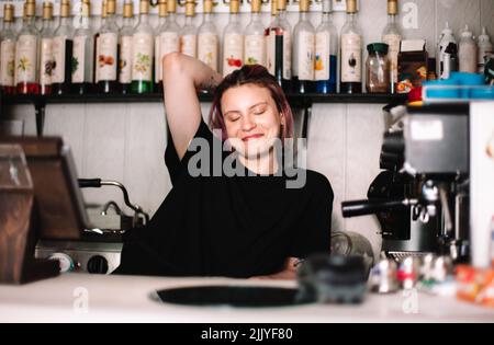Fröhliche junge Barista an der Kasse im Café Stockfoto