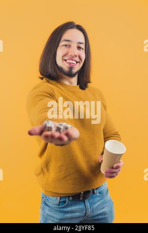 Ein hübscher europäischer Kerl mit Würfel und einem Papierbecher, der Freizeit in einem Studio verbringt. Hochwertige Fotos Stockfoto