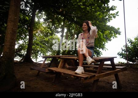 Frau, die an einem Tisch sitzt, umgeben von Licht und Natur Stockfoto