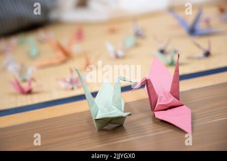 Zwei Origami-Kraniche, die die Schnäbel zusammenkleben Stockfoto