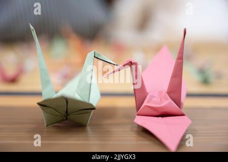 Zwei Origami-Kraniche, die die Schnäbel zusammenkleben Stockfoto