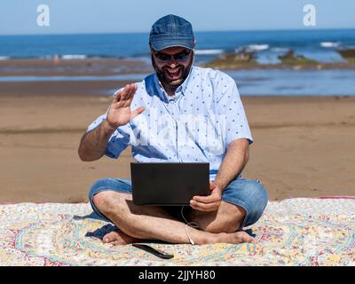 Mann im Urlaub macht einen Videoanruf vom Strand Stockfoto
