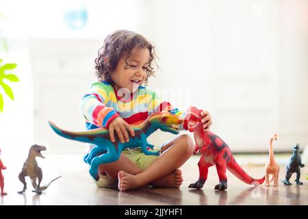 Kind spielt mit bunten Spielzeug Dinosaurier. Pädagogisches Spielzeug für Kinder. Kleiner Junge, der Fossilien und Reptilien lernt. Kinder spielen mit Dinosaurierspielzeug. Stockfoto