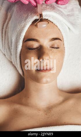 Frau, die eine Gesichtsmassage mit Jaderolle erhält. Gesichtsbehandlung für Mädchen. Hautpflege. Stockfoto