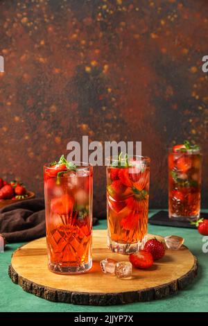 Brett mit Gläsern Erdbeerlimonade auf grünem Tisch vor grungenem Hintergrund Stockfoto