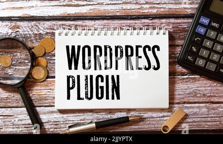 Business Concept.Text WordPress Plugin Schreiben auf Notizpapier mit Bleistift, Büroklammern und Brille auf gelbem Hintergrund. Stockfoto