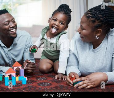 Es ist alles Spaß und Spiele zu Hause. Eine glückliche Familie spielt mit Holzklötzen zusammen zu Hause. Stockfoto