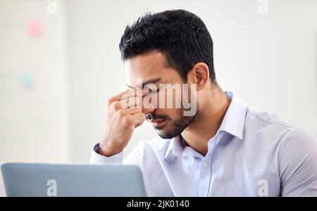 Gestresster, frustrierter und depressiver Geschäftsmann, der an Kopfschmerzen oder Migräne leidet und darum kämpft, eine Frist einzuhalten. Überarbeitet, verworckt und Stockfoto