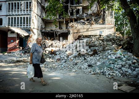 Charkiw, Ukraine. 8.. Juli 2022. Eine alte Dame kommt an einem Wohngebäude vorbei, das durch russische Artillerie-Streiks in Saltivka zerstört wurde. Der Bezirk Saltivka war einst einer der dichtesten besiedelten Bezirke in Charkiw und wurde heute zu Ruinen und Trümmern, da der Bezirk weiterhin unter heftigen Beschuss durch die russische Armee leidet. (Bild: © Alex Chan Tsz Yuk/SOPA Images via ZUMA Press Wire) Stockfoto