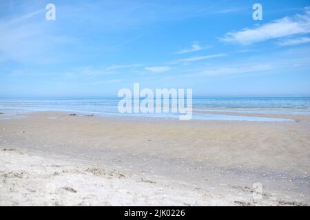 Schöner, natürlicher und landschaftlicher Blick auf den Strand und den blauen Himmel über dem Horizont mit Kopierfläche. Eine friedliche und ruhige Szene von endlosem Sandwasser Stockfoto