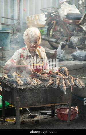 PHICHIT , THAILAND - AUGUST 29,2020 : nicht identifizierte ältere Anbieter grillen Wels zum Verkauf. Oder grillen auf dem Morgenmarkt Dieses Essen ist beliebt. Stockfoto