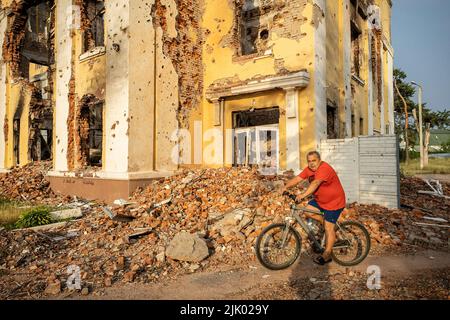 Charkiw, Ukraine. 08.. Juli 2022. Ein Mann auf dem Fahrrad fährt an den Ruinen einer Schule in Charkiw vorbei. Charkiw gilt als zweitgrößte Stadt der Ukraine, war eines der wichtigsten strategischen Ziele der russischen Invasion und seit Kriegsbeginn hat die Stadt mehrere Raketenangriffe erlitten, da die Beamten die Stadt als "Heldenstadt der Ukraine" bezeichneten. (Foto von Alex Chan Tsz Yuk/SOPA Images/Sipa USA) Quelle: SIPA USA/Alamy Live News Stockfoto