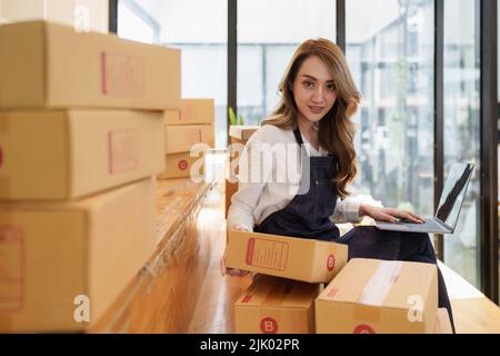 Junge asiatische Frau im Lager zur Lieferung an Unternehmer Eigentümer SME. Business digital online KMU Kleinunternehmen und Online-Shop. Stockfoto