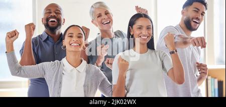 Wir haben allen Grund zum Feiern: Eine Gruppe von Geschäftsleuten, die im Büro fröhlich aussehen. Stockfoto