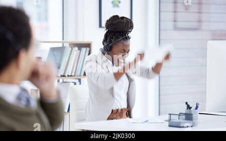 Eine junge Geschäftsfrau, die wütend auf einem Computer in einem Callcenter arbeitet. Stockfoto